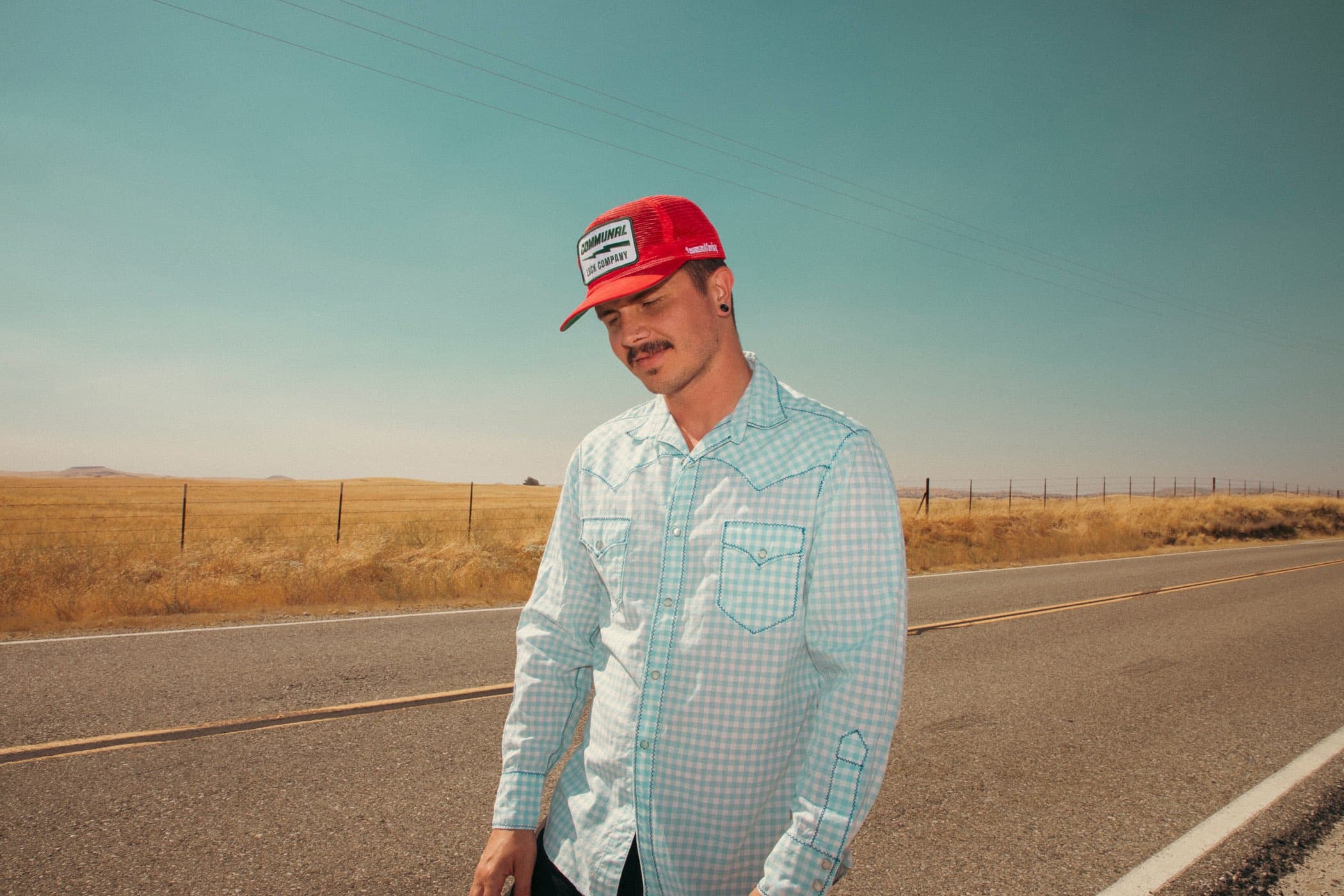 Bridger Scott, founder of Wylara, on a desert road in a red trucker hat and mint button-down